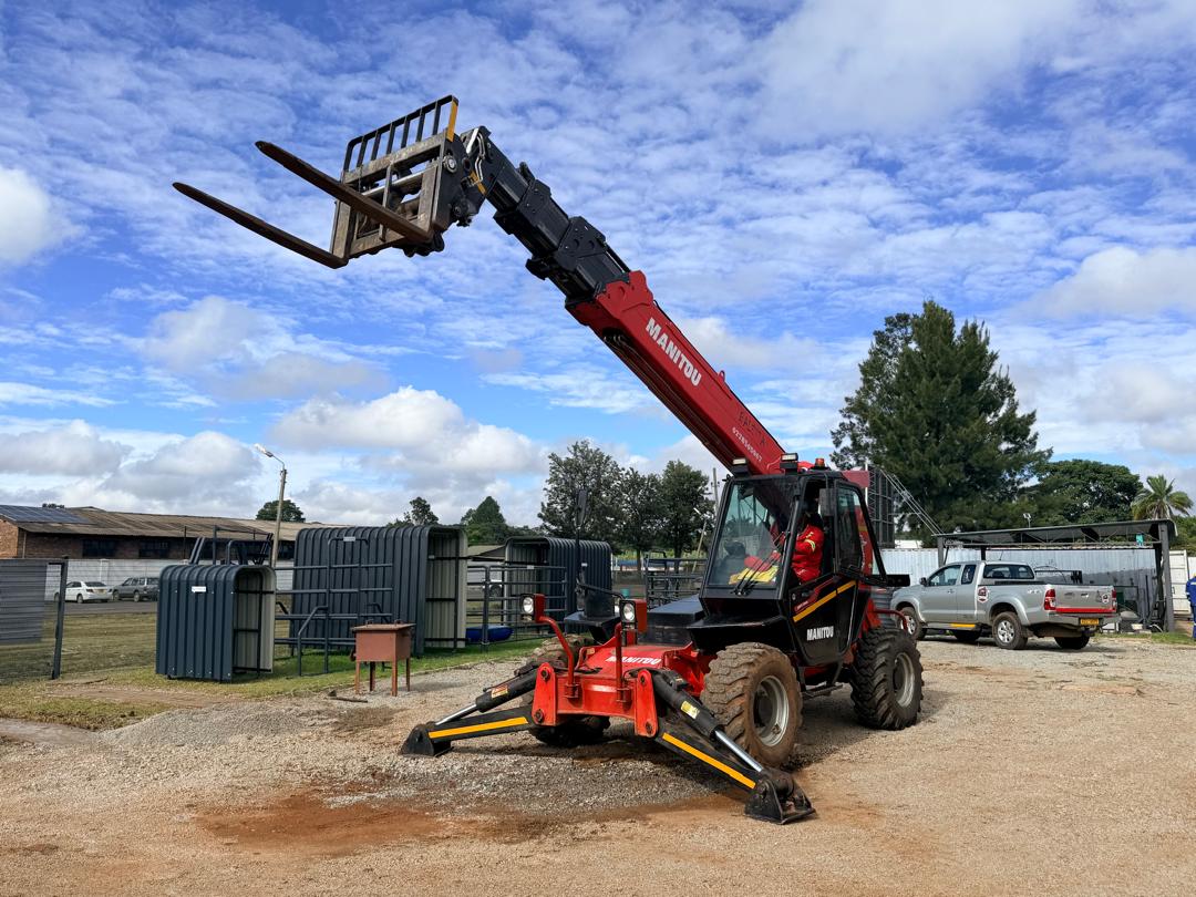 Manitou telehandler with forks lifting materials on a Harare site